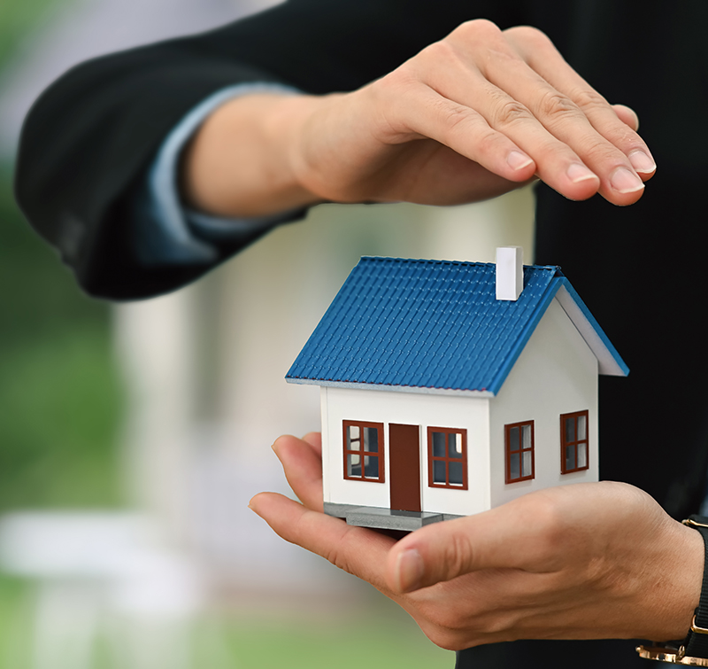 Businessman or real estate agent hands sheltering house model. Real estate investment, property insurance and security concepts.